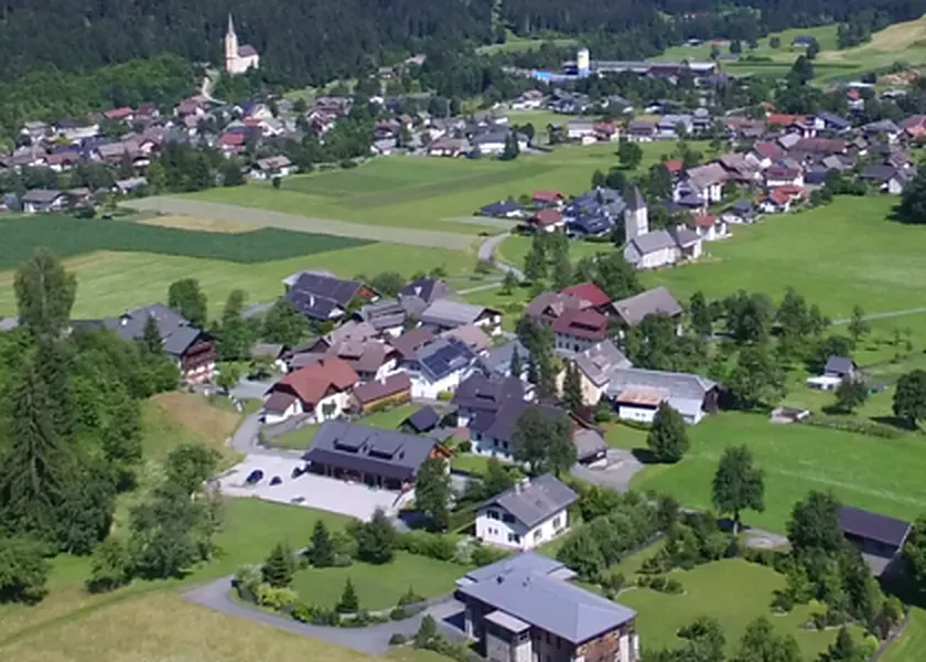 Luftaufnahme eines Kärntner Dorfes mit Kirche, Häusern und Wiesen